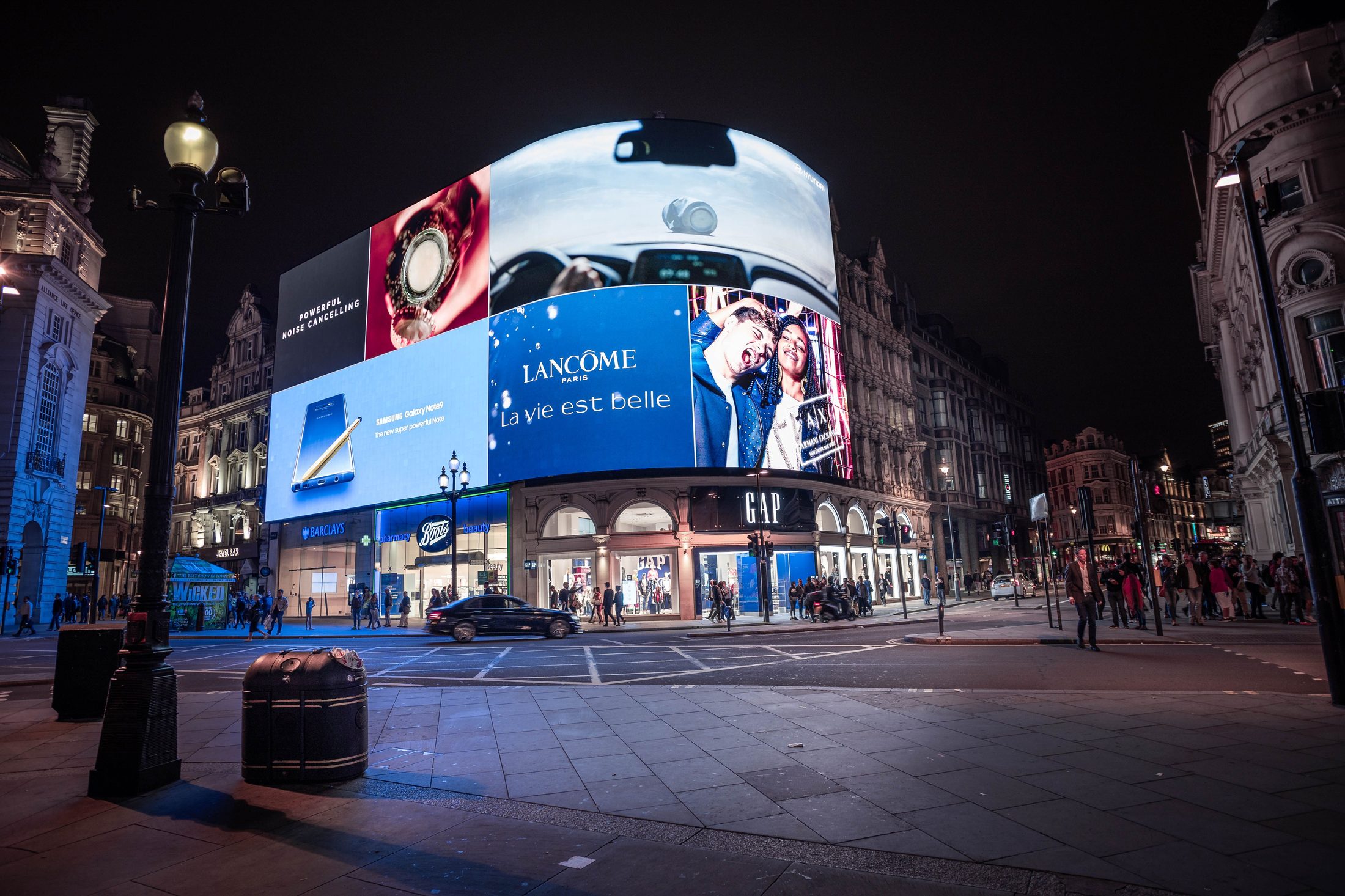 Illuminated advertising screens above a city intersection at night